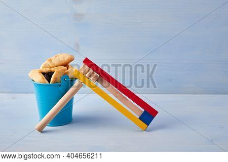 Purim Celebration Concept With Hamantashen Cookies, Purim Toy Noisemaker On Blue Background