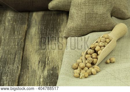 Chickpea Grains In A Bag On A Wooden Background With Space For Text. Chickpea Seeds On A Wooden Spoo
