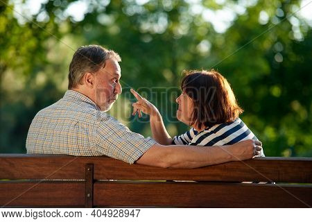 Back View Mature Couple Fooling Around On The Bench. Retired Man And Woman Having Fun In The Park.