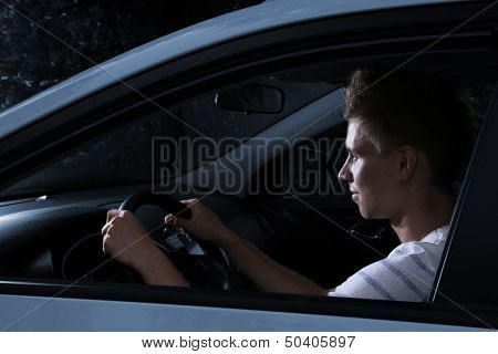 Young man driving in his car at night