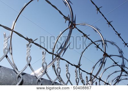 Barbwire and razor wire against blue sky
