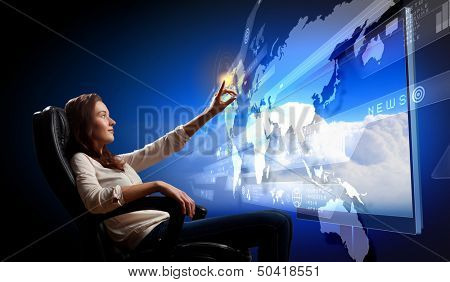 Young woman in armchair pushing icon on media screen