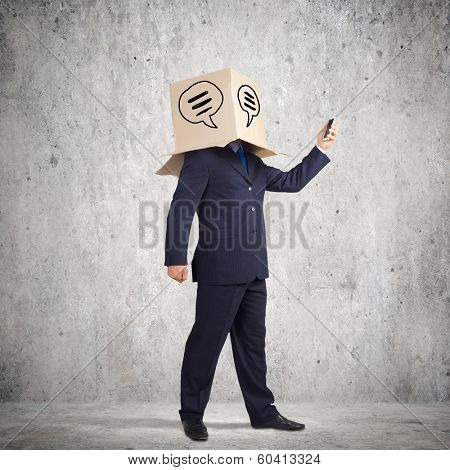Businessman using mobile phone wearing carton box on head