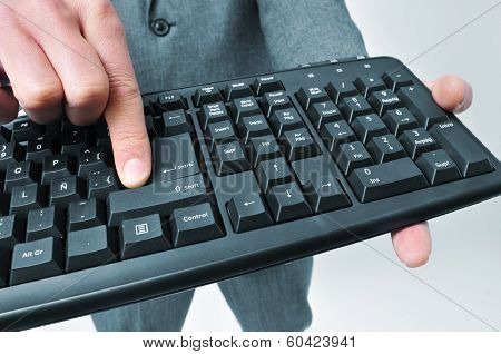 man wearing a suit pressing the enter key of a computer keyboard