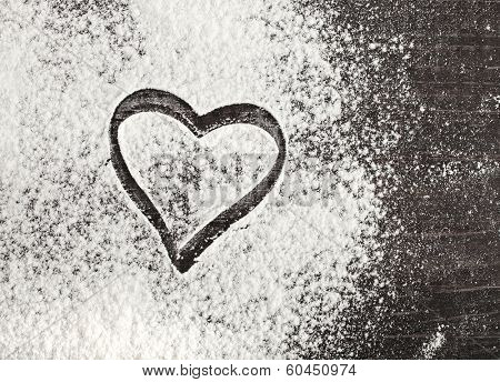 wheat flour with heart shape on the black surface table. top view 