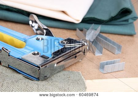 Construction stapler with fabric and staples on cork board close up