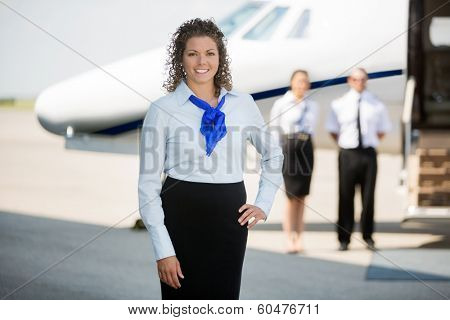 Portrait of confident airhostess with hand on hip standing at airport terminal