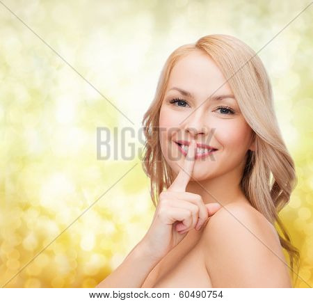 health and beauty concept - clean face of beautiful young woman pointing finger to her lips