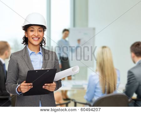 building, developing, consrtuction and architecture concept - smiling businesswoman in white helmet with clipboard and blueprint at office