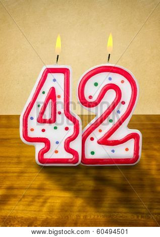 Burning birthday candles number 42 on a wooden background