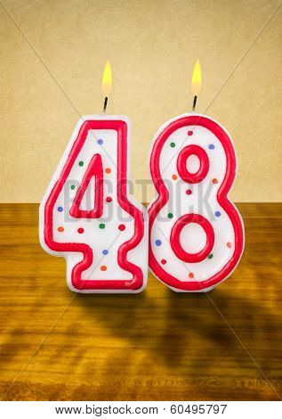 Burning birthday candles number 48 on a wooden background