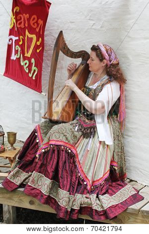 MUSKOGEE, OK - MAY 24: Woman dressed in vintage clothes plays harp at the Oklahoma 19th annual Renaissance Festival on May 24, 2014 at the Castle of Muskogee in Muskogee, OK 