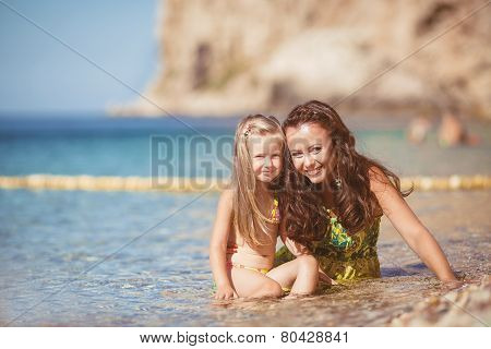 Happy mom and her adorable little daughter during summer vacation on the beach