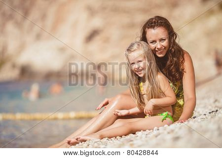 Happy mom and her adorable little daughter during summer vacation on the beach