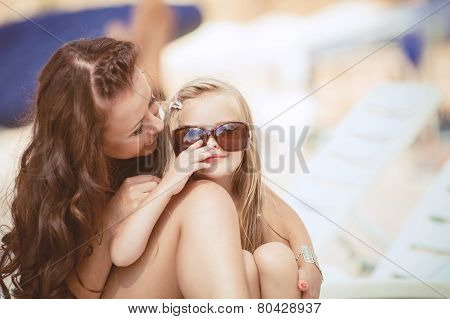 Happy mom and her adorable little daughter during summer vacation on the beach