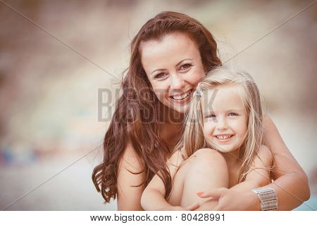 Happy mom and her adorable little daughter during summer vacation on the beach