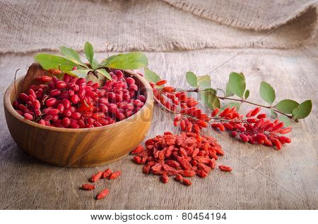 Barberry With Leaves And Dry Goji Berries On Wooden Background