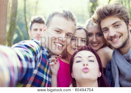 Young people having good time together in park on river and taking selfie