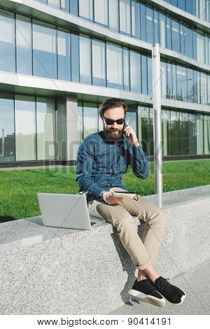 Young Businessman In Sunglasses With Coffe Laptop Talking Phone Outdoors
