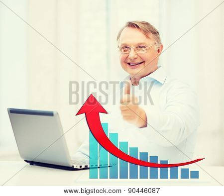 technology, oldness, people, success and business concept - old man in eyeglasses with laptop computer showing thumbs up over office background and growth chart