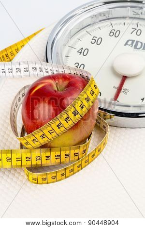 on a bathroom scale is an apple. symbolic photo for slimming and healthy, vitamin-rich diet.