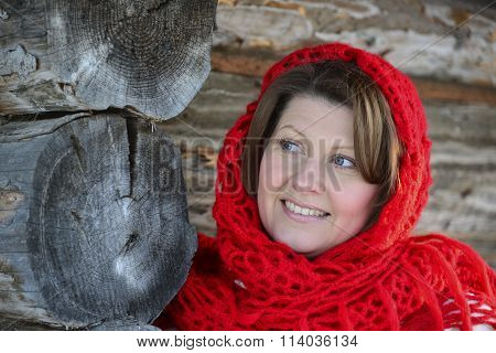 The Russian woman in a shawl warms hands near an izba