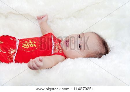 Cute five months asian baby smiling in red cheongsam. on bright soft carpet