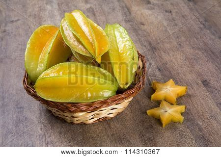 Some Caramboles In A Basket Over A Wooden Surface