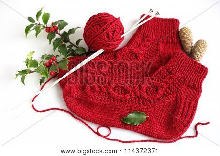 Red knitting homemade socks with holly branch