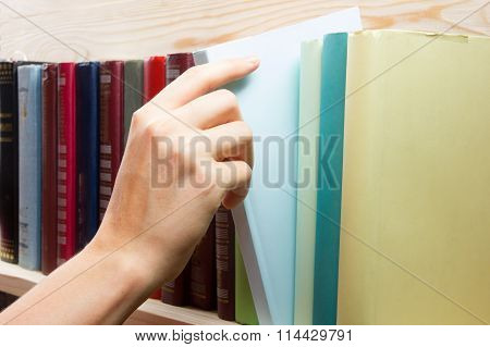 Women Hand selecting book from a bookshelf in library. Back to school.