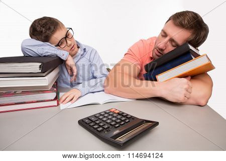 Father and son sleeping on books at the table