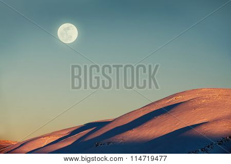 Beautiful winter landscape, amazing view on the moon by day over mountains covered with snow, stunning wintertime nature