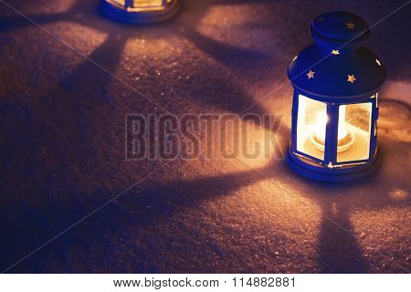 Two Lantern with burning candle on snow in the evening. Tinted p