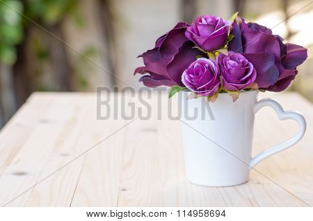 Purple artificial rose in cup heart shape handle for love.