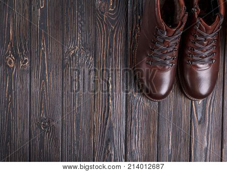 Still life with men's leather dark brown shoes. Men's boots on wooden background view from above flatlay