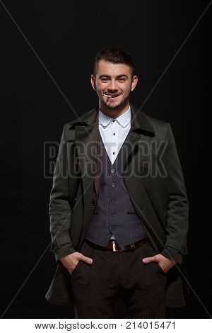 A man on a black background, retro style, stands with a cigarette in his mouth, smiles, putting his hands in his pockets, looking at the camera. .