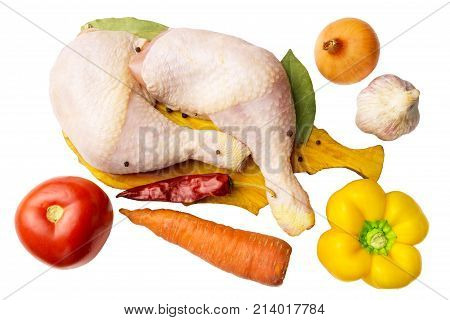 Two raw chicken legs at cutting board with spices and vegetables such as tomato carrot pepper garlic red chili pepper onion isolated on white top view.