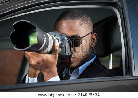 Private Detective Sitting Inside Car Photographing With SLR Camera
