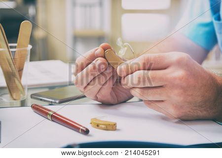 Doctor audiologist holding hearing aid in his hand