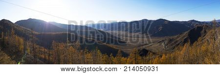 Fantastic panorama of a large mountain range. The bright sun gives beautiful color and depth. The winding mountain road. The autumn time of the year.