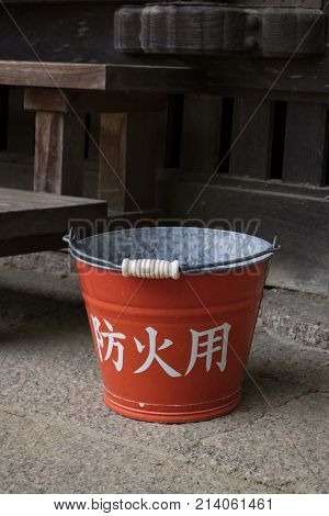Nara, Japan -  May 31, 2017: Traditional red fire bucket with water in front of the wooden temple as fire prevention  