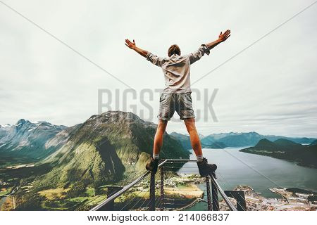 Man raised hands balancing at the edge cliff Rampestreken landmark in Norway mountains Travel lifestyle risk concept active vacations happy tourist enjoying landscape aerial view