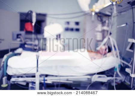 Male patient lyng in the bed in the hospital's intensive care unit unfocused background.