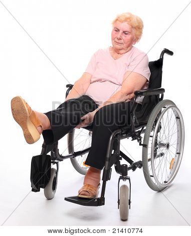 Ältere gelähmter Frau sitzt in einem Rollstuhl auf einem weißen.