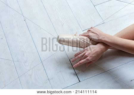 Closeup of young ballerina legs in pointe shoes at white wooden floor background, with copy space. Ballet practice. Beautiful slim graceful ballet dancer.