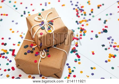 Present boxes with white bow on white background with multicolored confetti. Christmas and new year concept