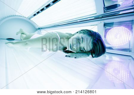 Beautiful sexy brunette woman sunbathing in solarium
