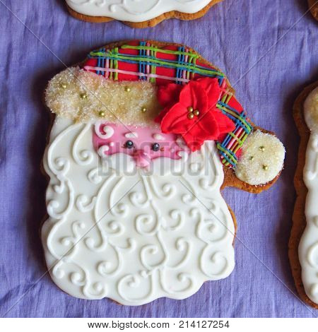 Glazed Christmas gingerbread hand-painted in a form of Santa-Klaus head in hat on dark blue background
