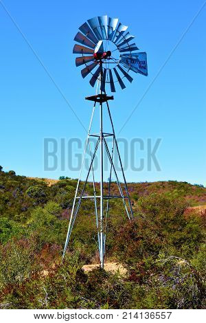 October 15, 2017 in Santa Barbara, CA:  Rural ranchland with a rustic vintage windmill amongst chaparral shrubs taken in the rural Santa Barbara County, CA where people can buy many acres farmland and rural landscape