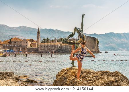 BUDVA, MONTENEGRO - August 18, 2017: Statue of a ballerina in an Arab position and a girl. Mogren beach. The background is blurred - the old town of Budva, Montenegro.